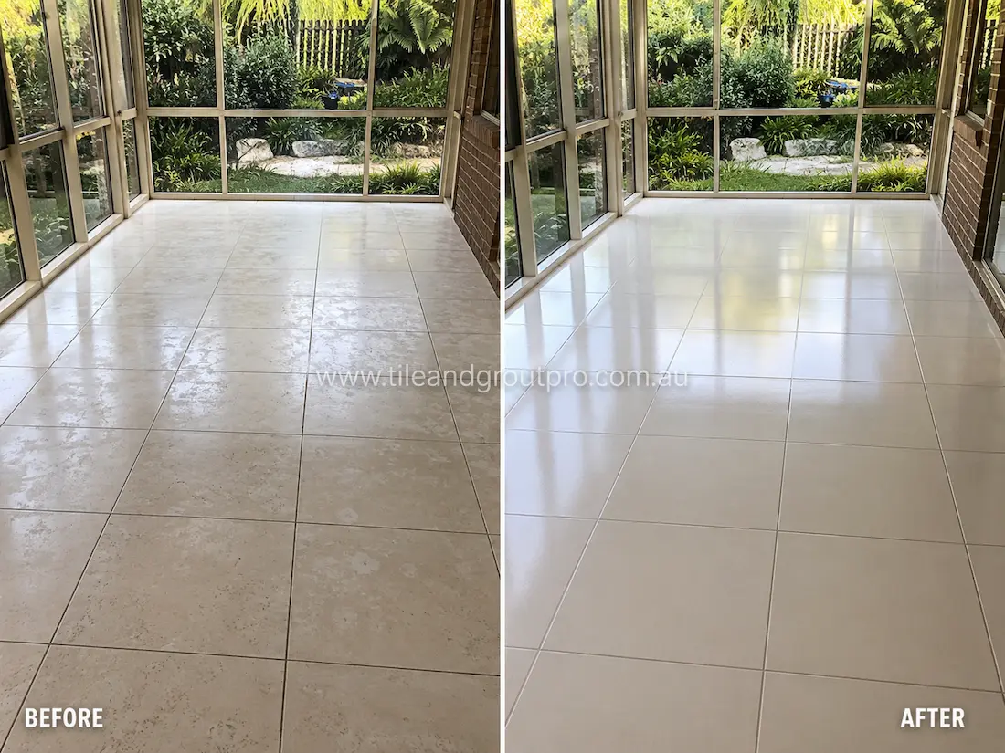 Bright enclosed sunroom with cream ceramic floor tiles before sealer stripping, showing uneven sealer residue and cloudy tile surfaces near large garden-facing windows.