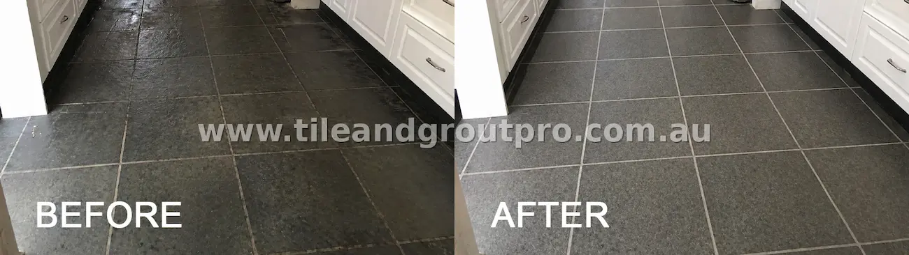 Dark stone kitchen floor tiles with visible grime buildup and dull finish before tile and grout cleaning