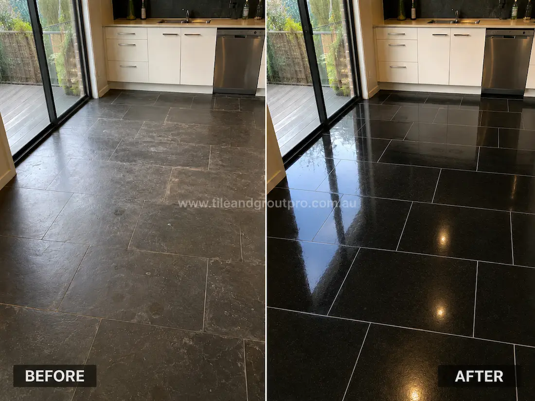 Before stone polishing, the black bluestone kitchen floor showed dull patches, surface haze, and reduced shine near white cabinetry and sliding glass doors.