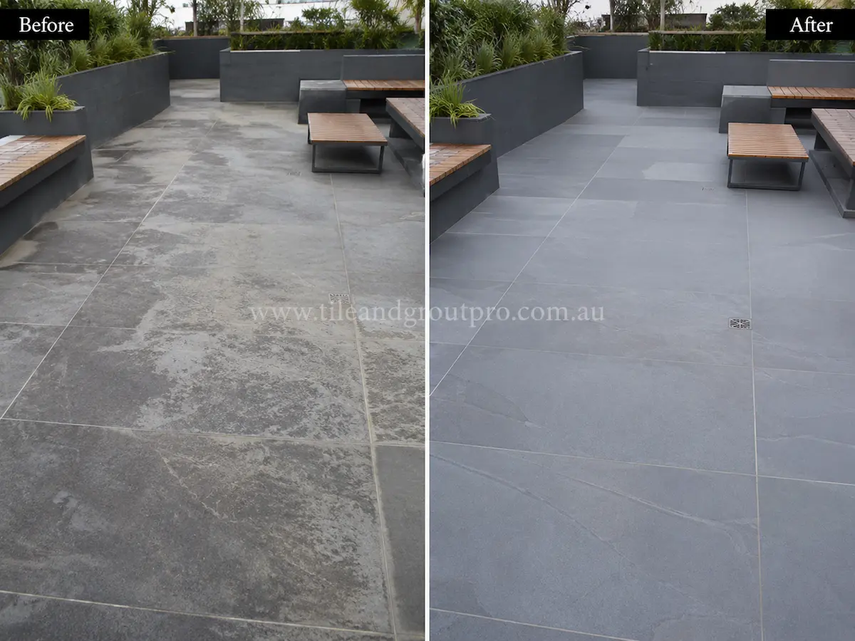High-rise balcony with bluestone floor tiles before sealer stripping, showing uneven sealer haze and weathered grey stone surfaces beside glass balustrades.