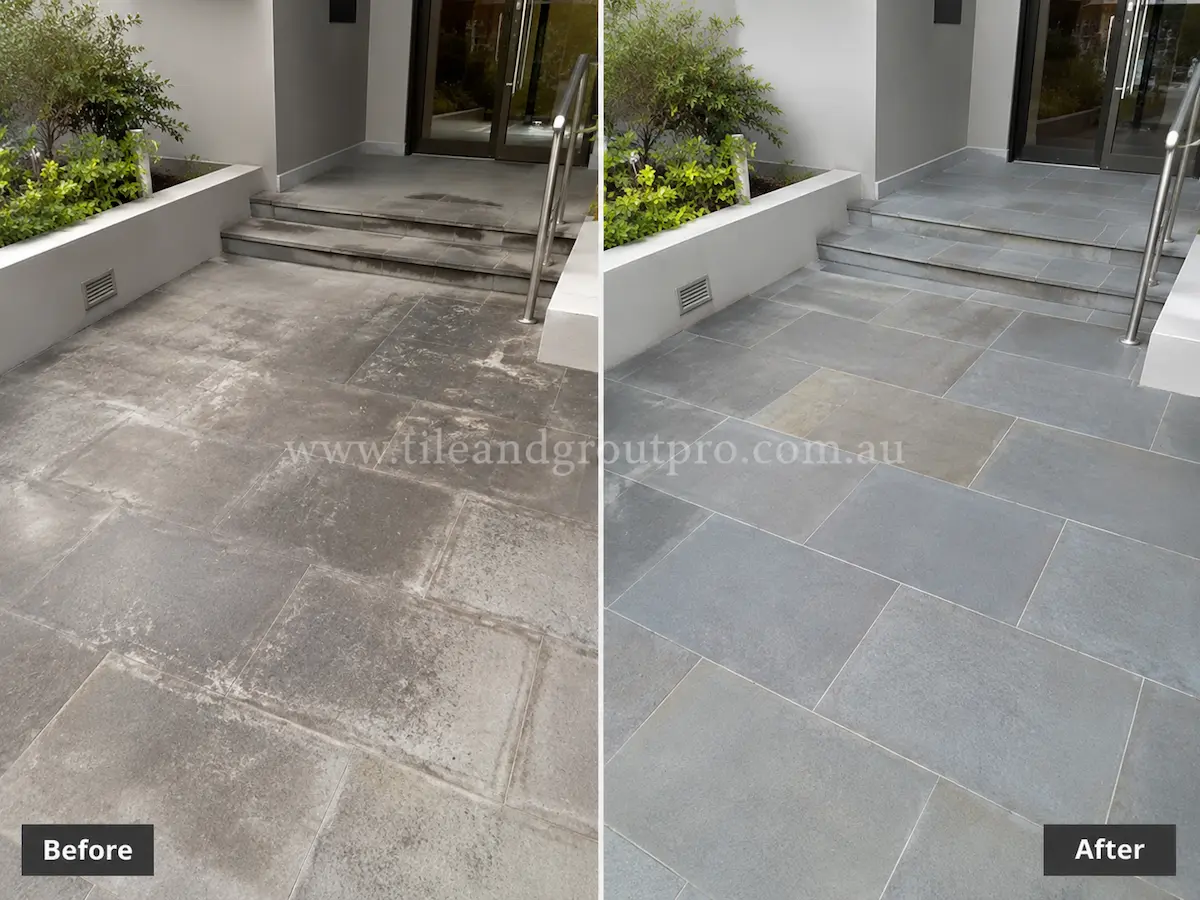 Residential outdoor entryway with bluestone tiles before sealer stripping, showing faded grey stone surfaces and sealer build-up around front steps and landscaped planters.