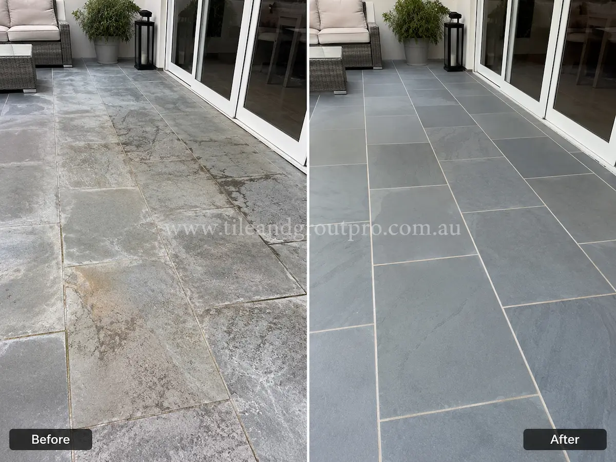 Outdoor bluestone patio before sealer stripping with cloudy sealer build-up and dull grey stone tiles beside white framed glass doors and outdoor furniture.