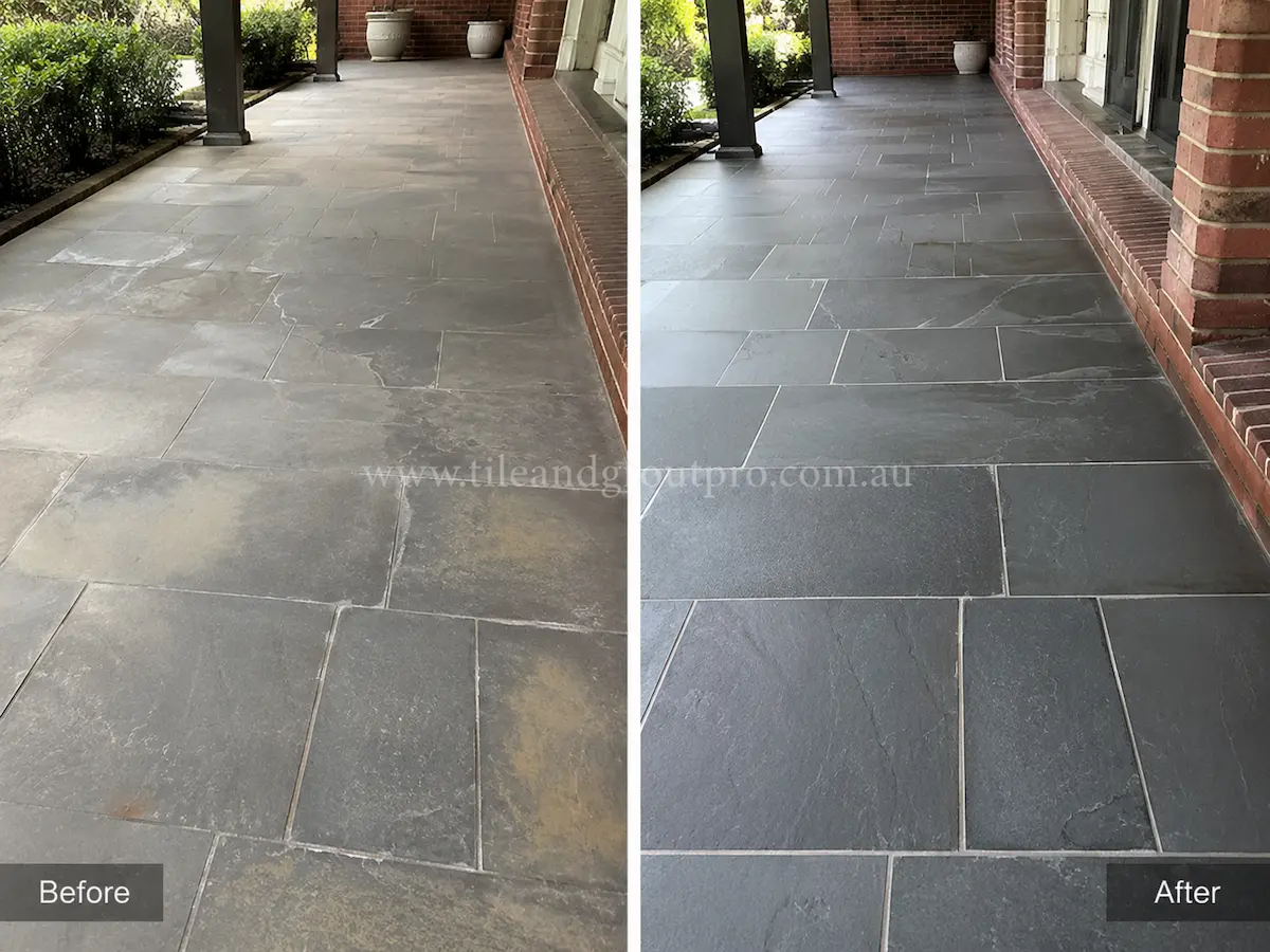 Modern rooftop terrace with bluestone paving before sealer stripping, showing cloudy sealer build-up and dull grey stone tiles around outdoor seating and planter boxes.