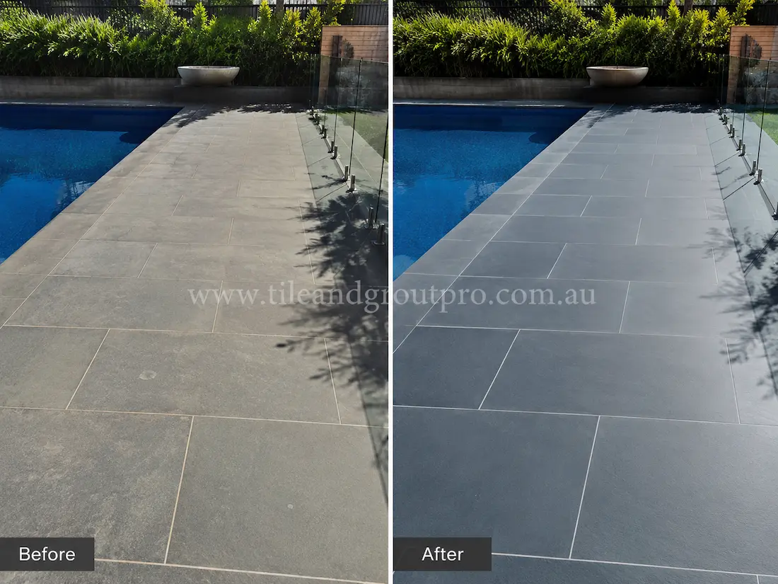 Before tile renewal, outdoor bluestone poolside tiles around a modern swimming pool showed faded colouring, surface haze, and weathered natural stone finishes beside the glass pool fence.