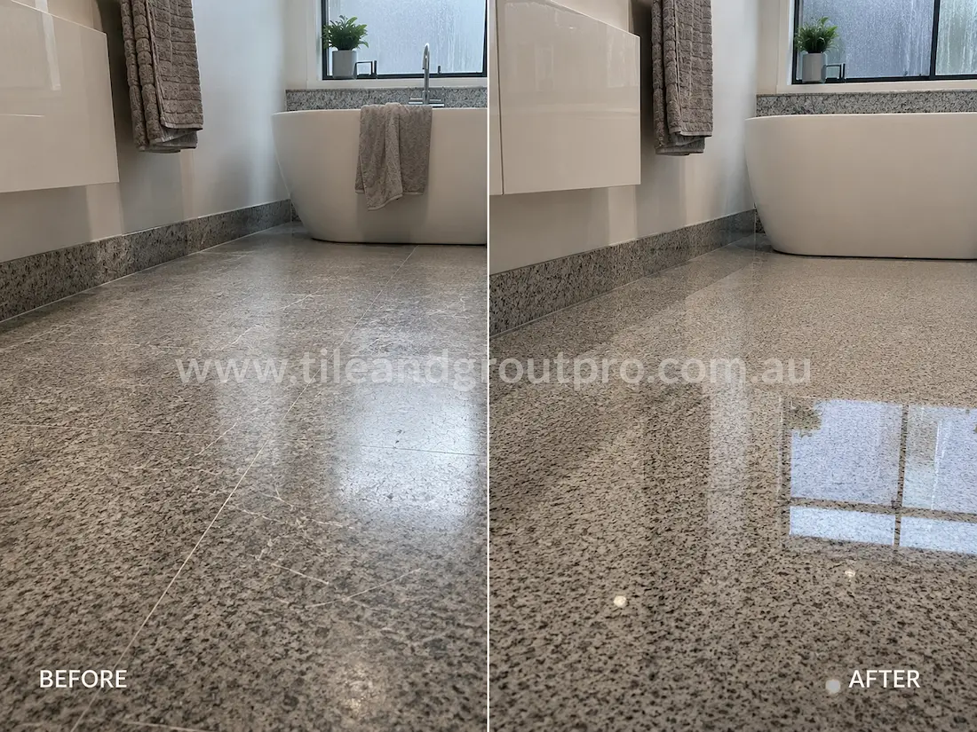 Modern bathroom grey granite floor before grinding, showing scratched stone tiles, dull finish, and low reflectivity beside the freestanding bathtub.