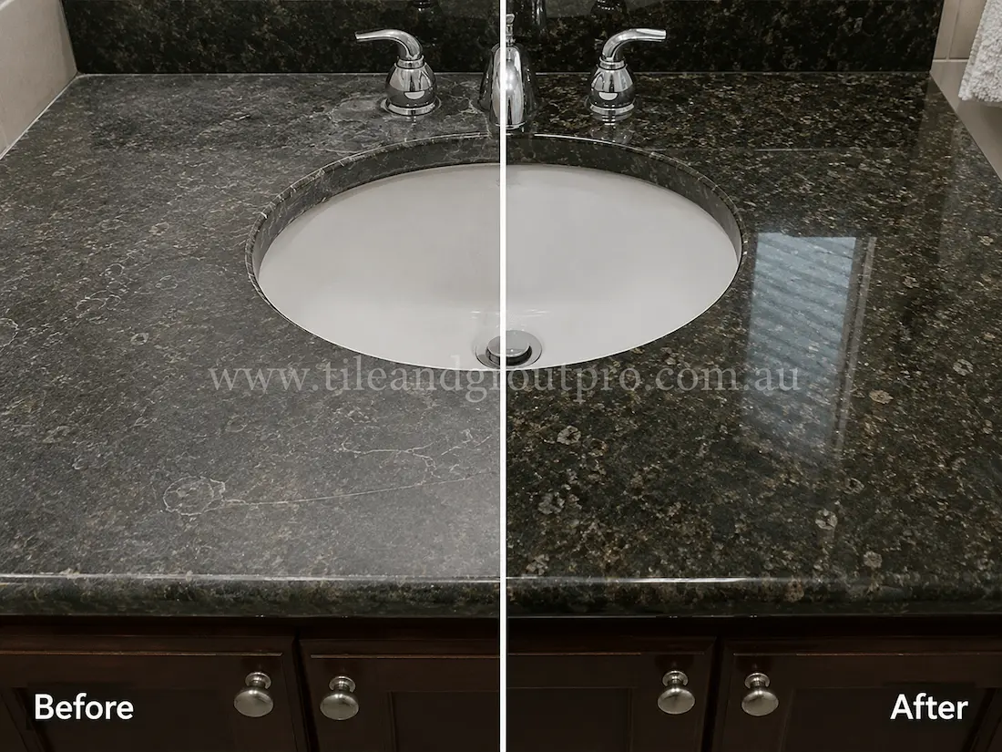 Black granite bathroom vanity countertop with an undermount sink, showing etching, water spotting, and a worn matte appearance before granite resurfacing and polishing.