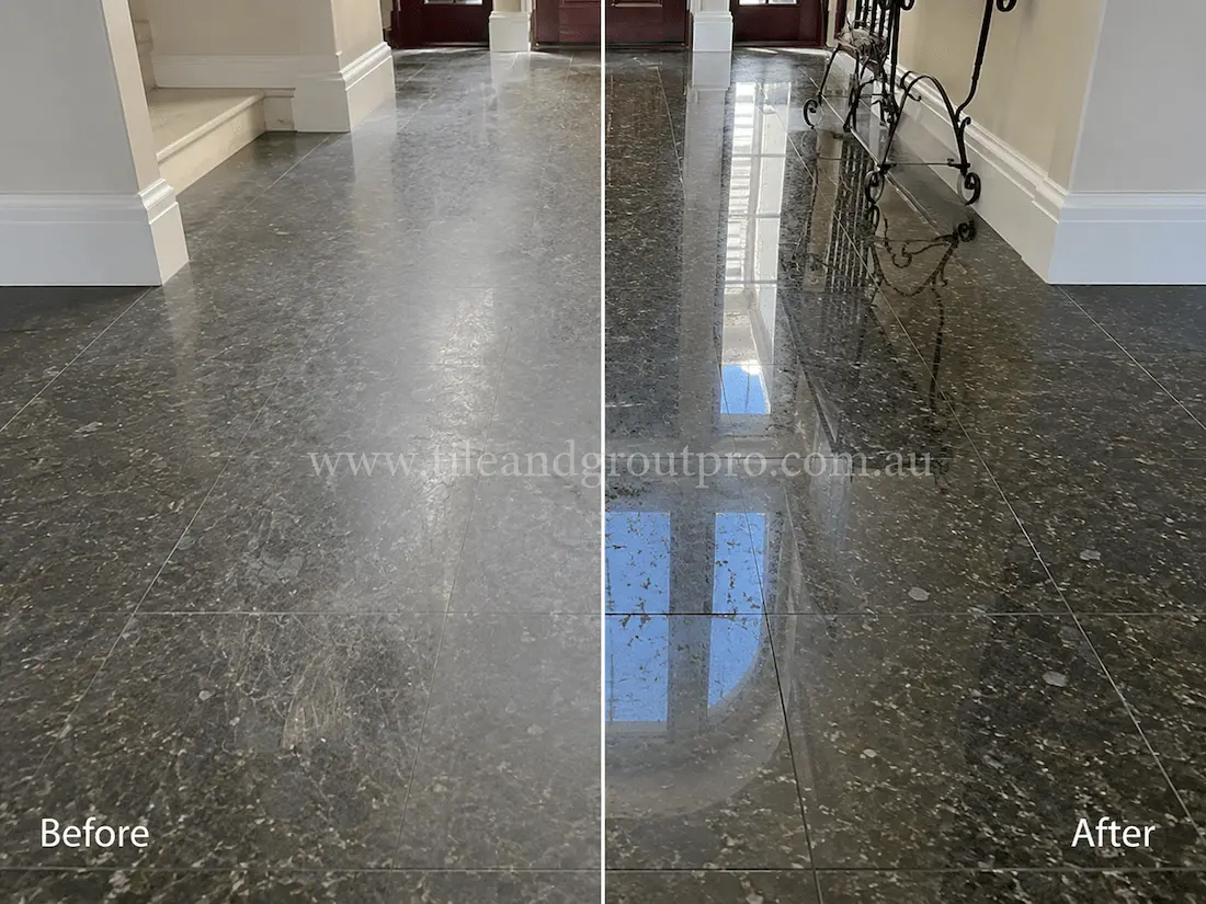Residential entry hall with polished black granite floor tiles displaying heavy traffic wear, dullness, and visible surface scratches before tile resurfacing.