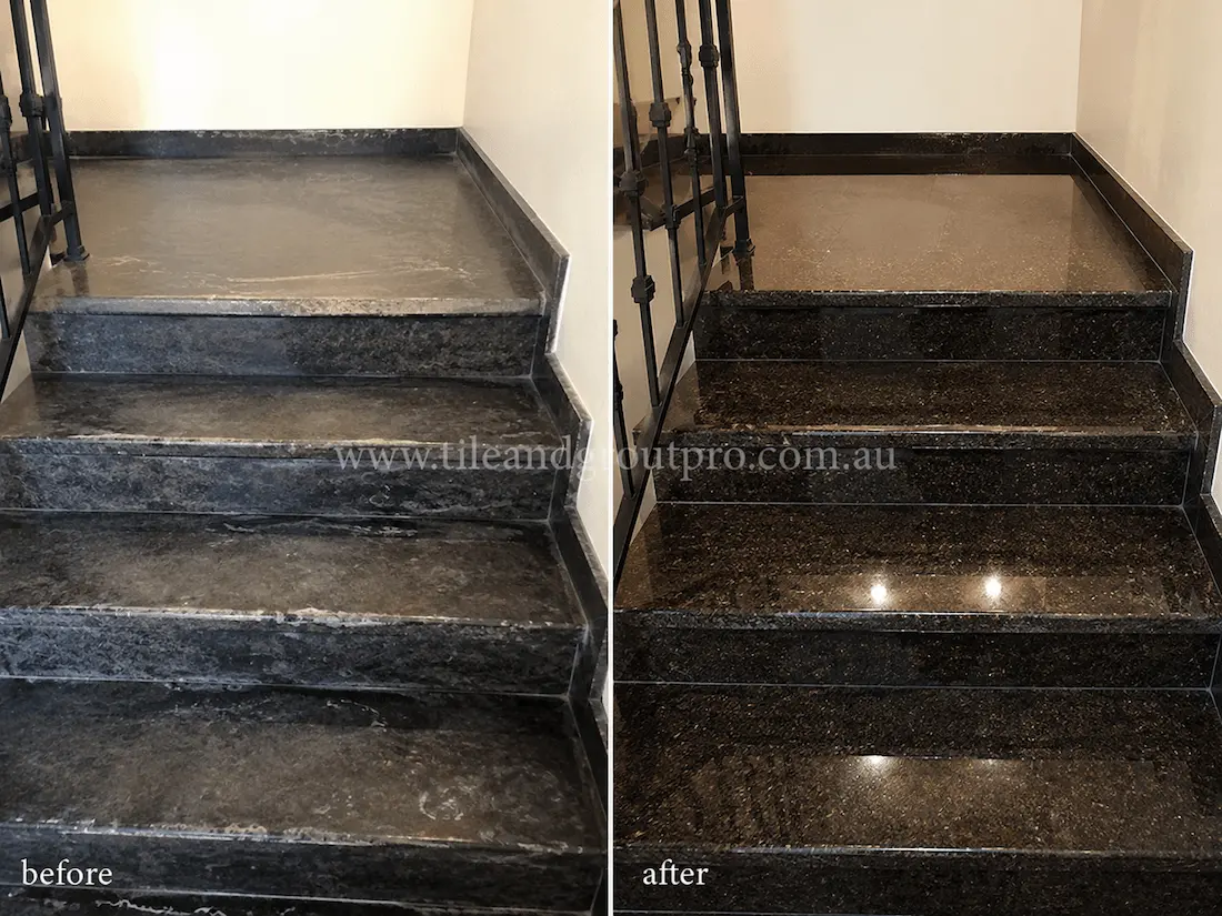 Black granite staircase and landing tiles with visible surface etching, scuff marks, and a faded finish before granite tile resurfacing and high-gloss restoration.