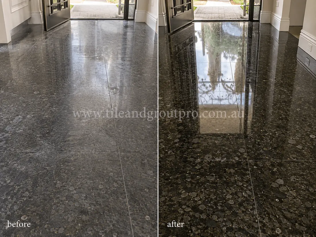 Black granite tile entryway floor at a residential front entrance, showing dull wear, light scratching, and reduced reflectivity before professional granite tile resurfacing and polishing.