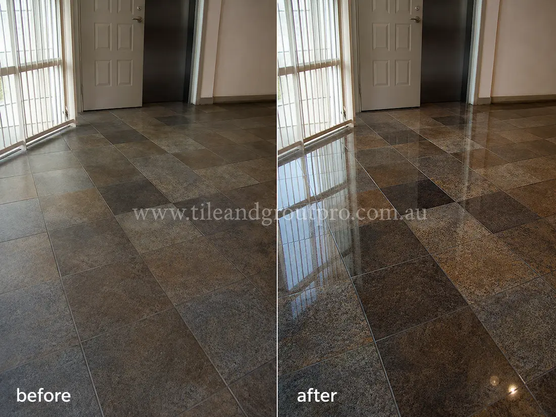 Before stone polishing, the dark slate-look porcelain entry floor tiles appeared dull and low-sheen with visible wear in a residential foyer beside vertical blinds and a white entry door.
