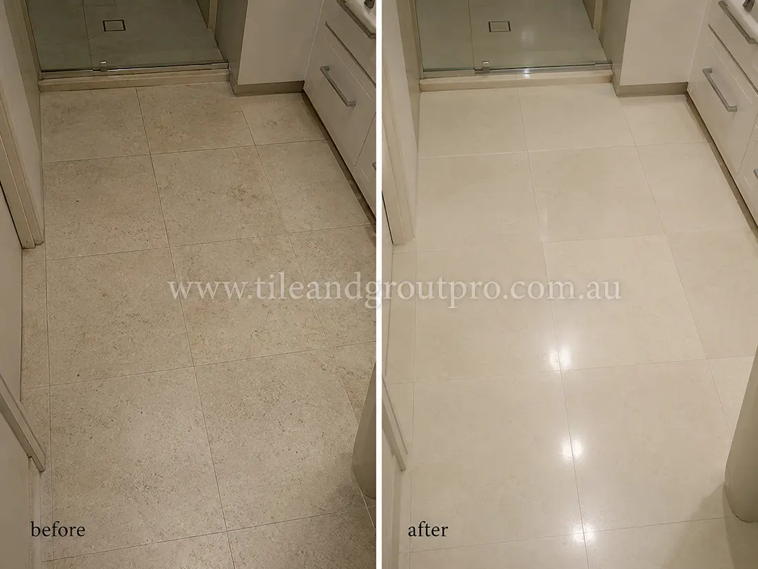 Cream limestone bathroom floor tiles near shower area with dull finish and light wear before professional stone polishing.