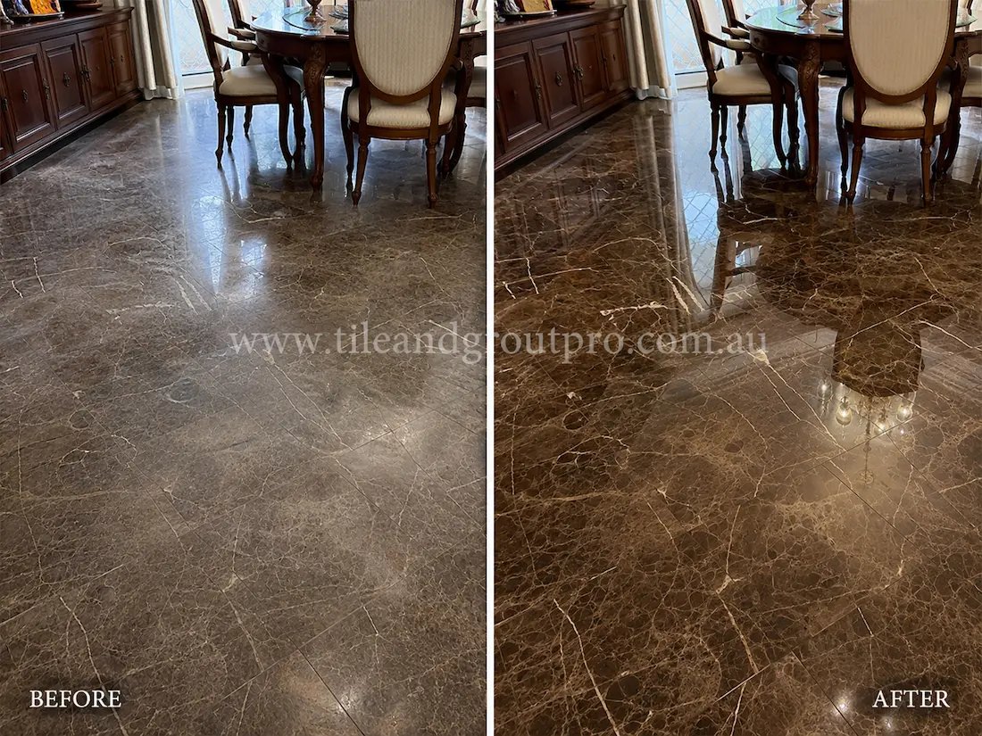 Dark Emperador marble floor in a residential dining room showing dull patches, light etching, and reduced shine around furniture before tile resurfacing and polishing.