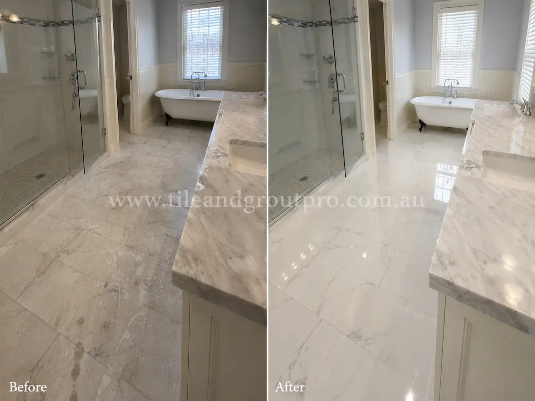 Before tile renewal, the marble bathroom floor and vanity surfaces showed dullness, etching, and water marks around the shower and bathtub area.