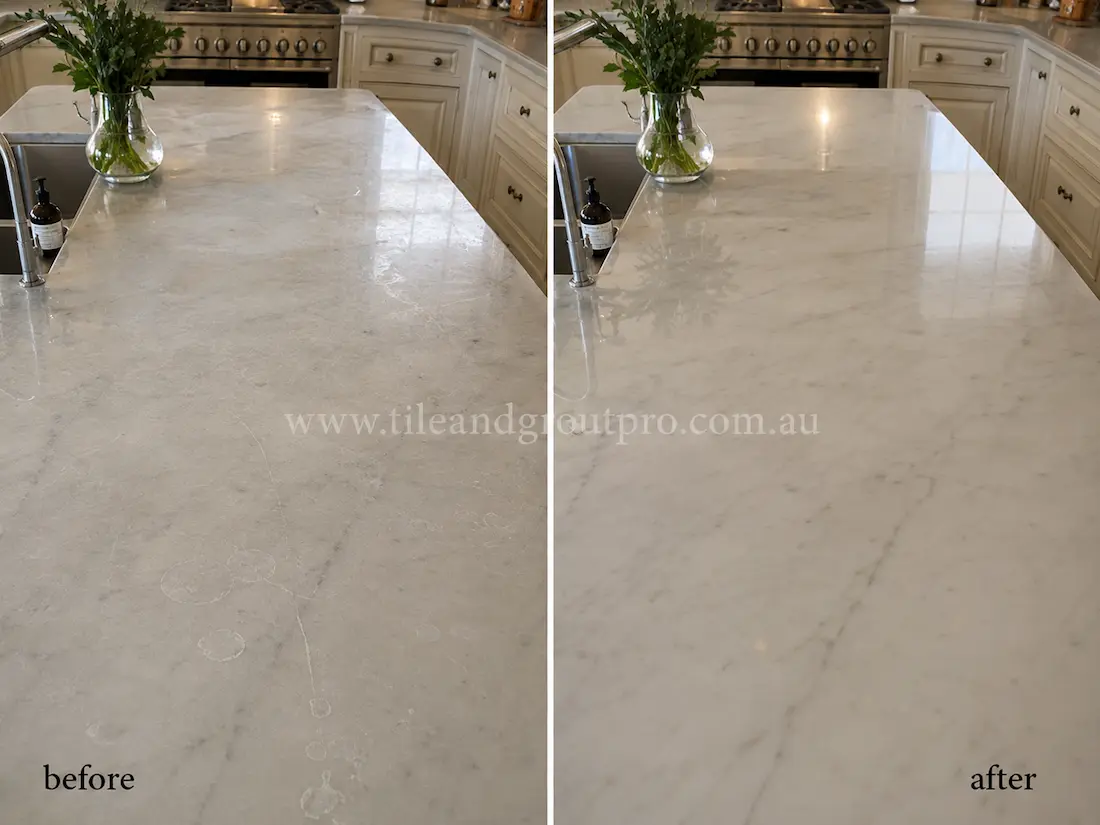 Large marble kitchen island countertop with visible etch marks, water spots, and a dull finish before tile resurfacing and polishing.