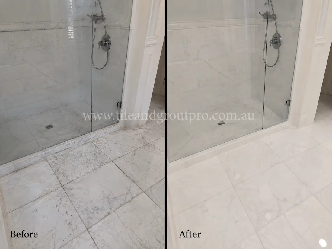 Before tile renewal, the marble shower floor and wall tiles showed soap scum buildup, dull patches, and water staining inside a glass shower enclosure.