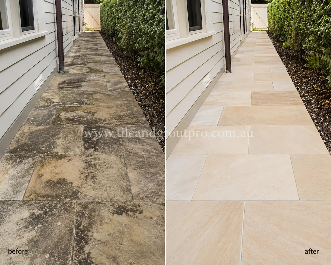 Before sandstone tile resurfacing, this narrow side-house walkway features cream sandstone paving with heavy black staining, organic growth, weathering, and surface discoloration along a residential garden passage.