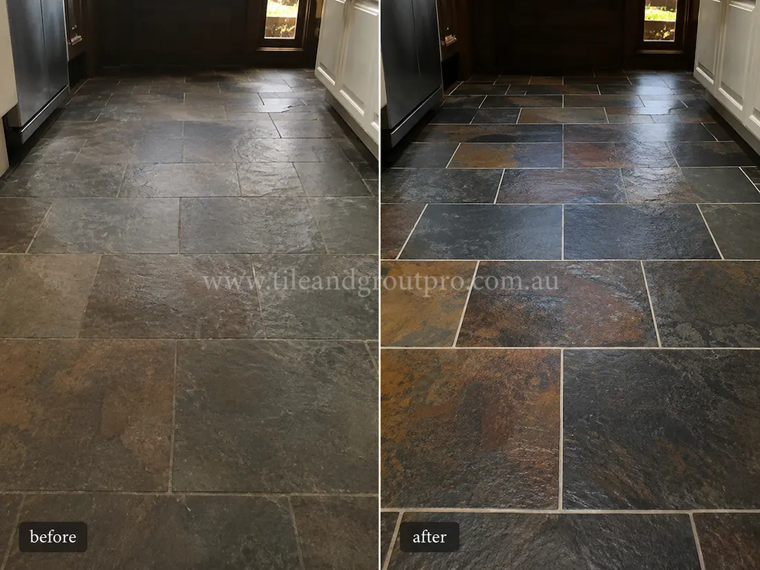 Before stone polishing, an interior slate tile kitchen and entry floor showed a dull, worn finish with muted charcoal, grey, and rust tones, reduced colour contrast, and a lack of depth across rectangular natural slate tiles between cabinetry and appliances.