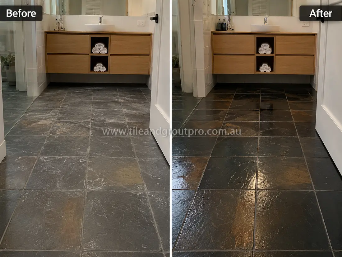 Before stone-polishing of natural slate bathroom floor tiles with cloudy patches, low sheen, and worn stone surfaces beneath a floating timber vanity.