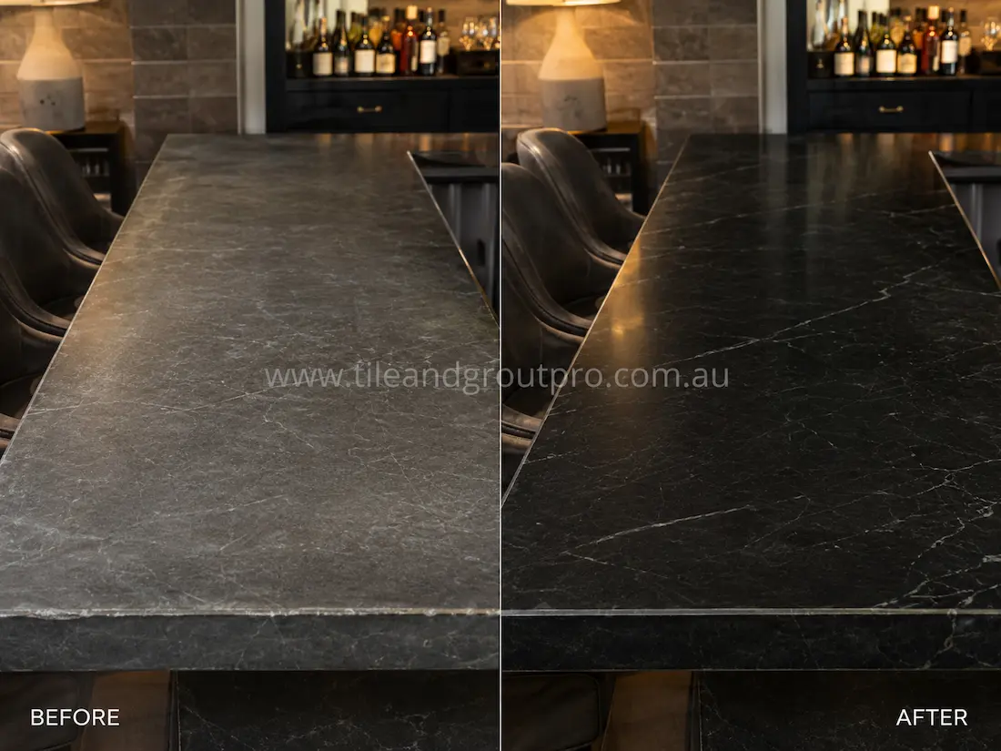 Before stone-polishing, the dark soapstone bar and dining tabletop had a dull, faded surface with light etching and minimal sheen in a modern interior setting.