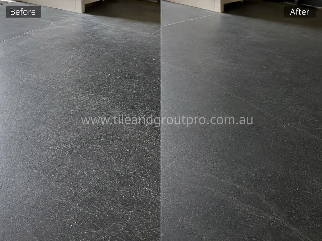 Dark soapstone floor tiles with fine scratches and wear marks before professional scratch removal service.