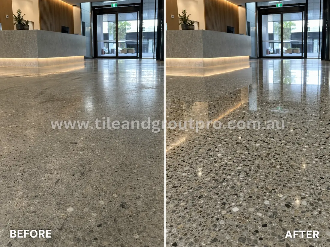 Commercial lobby terrazzo floor before grinding, showing a dull exposed aggregate surface with scratches and low reflectivity near the reception desk and glass entry doors.