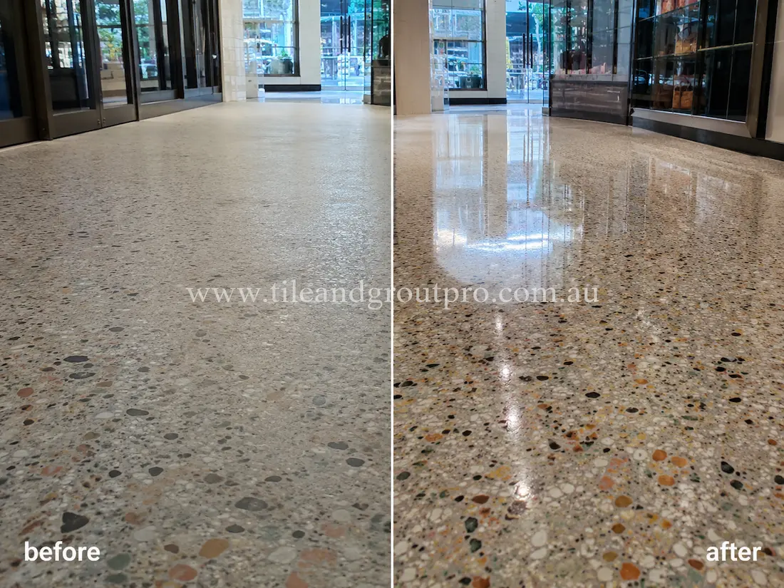 Before stone polishing, the terrazzo floor in a commercial lobby entrance appeared dull and low-sheen with muted aggregate detail and minimal light reflection near glass storefronts.