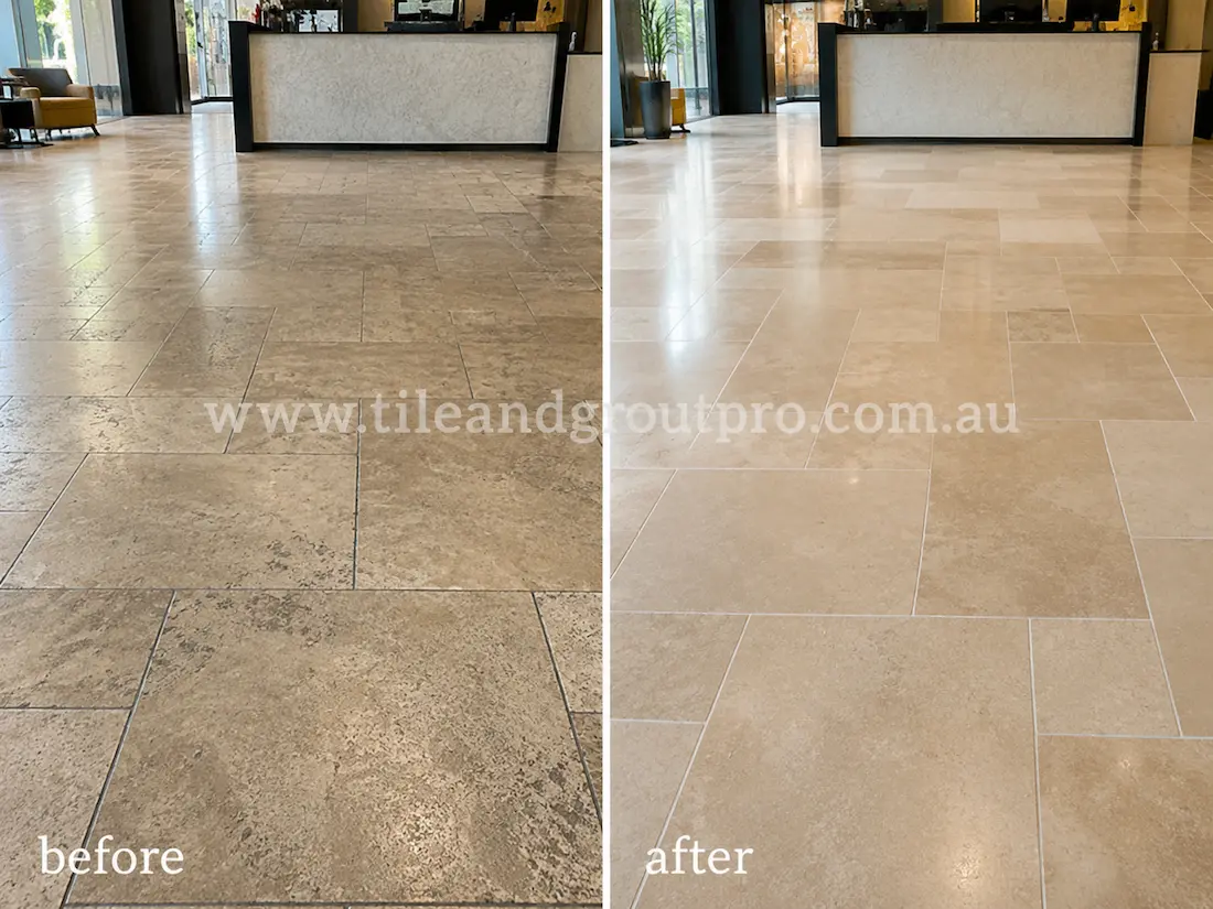 Commercial lobby travertine floor before grinding, showing dull stone tiles, traffic wear, darkened grout lines, and uneven finish near the reception desk.