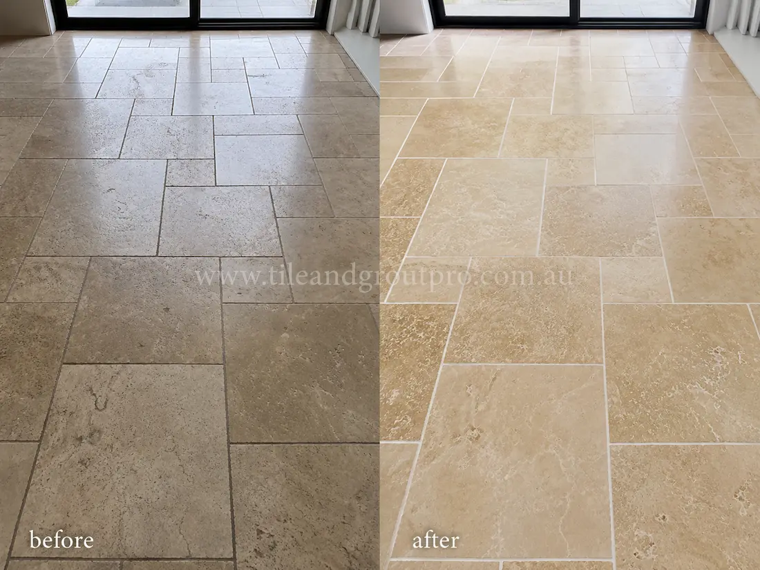 Living room travertine floor before grinding, displaying faded stone tiles, light scratches, and a worn matte finish near the sliding glass doors.